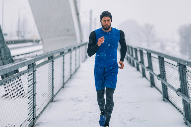 istock Man running on bridge during a winter snow day. 1363172518