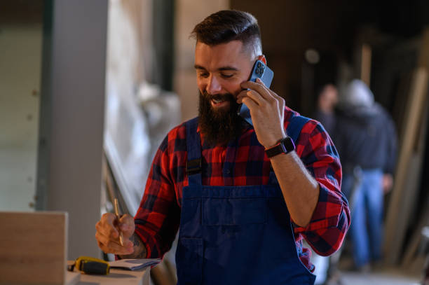 istock Young male carpenter working in workshop and using smartphone 1363172551