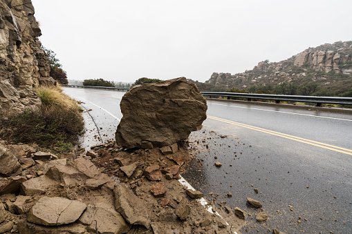 Rock from rain storm landslide blocking traffic lane on Santa Susana Pass Road in Los Angeles, California.