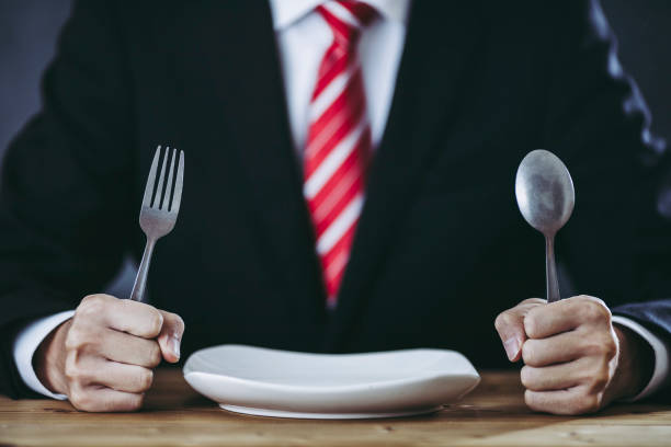 istock Businessman having a meal with a spoon and a fork 1363195902