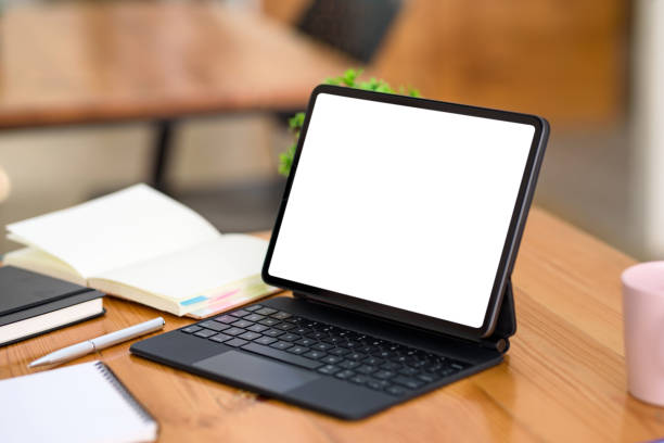 istock Digital tablet blank white screen with keyboard on wooden table. Mock up. 1363196947