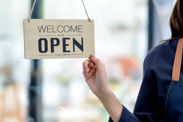 istock Happy young business owner standing with open sign board. 1363196964