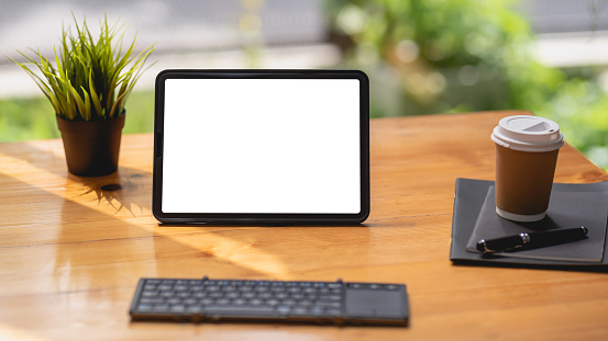 Tableta digital pantalla blanca en blanco con teclado sobre mesa de madera. Maqueta. photo