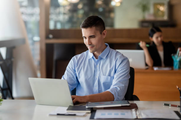 istock Businessman sitting working on laptop in office. 1363197349