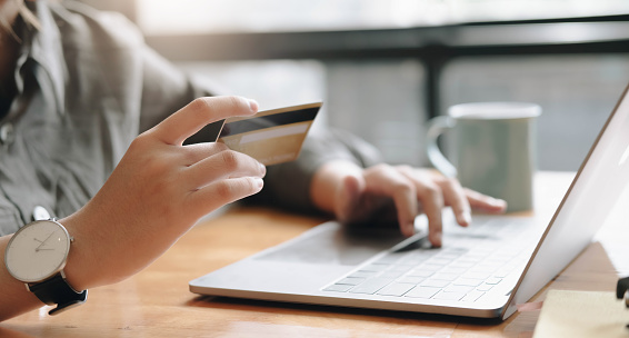 Pago en línea, manos de mujer sosteniendo una tarjeta de crédito y usando una computadora portátil para compras en línea con tono de filtro vintage photo