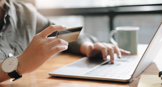 Online payment,woman's hands holding a credit card and using laptop computer for online shopping with vintage filter tone