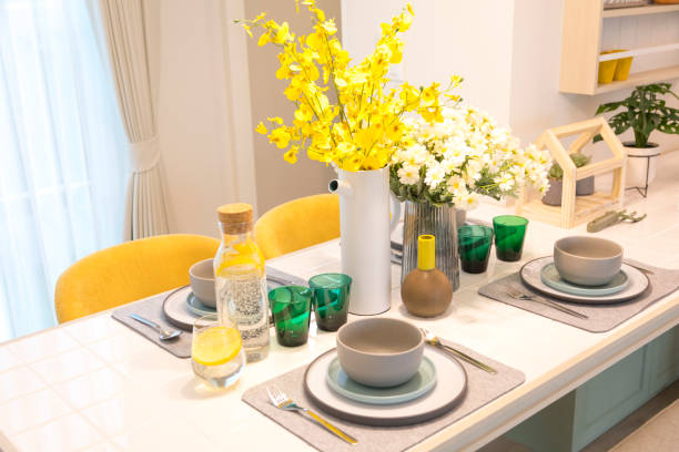 Dining table with green and yellow plate setting with flower in modern home.