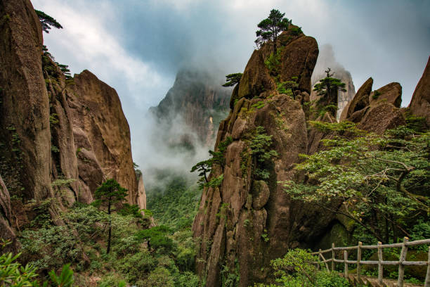 Dreamy Clouds and Fog Over the Beautiful Yellow Mountain A serene and inspiring scene shoot at the peaks of Mount Huangshan in Anhui province, China huangshan mountains stock pictures, royalty-free photos & images