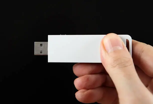 USB Drive in the Hand on the Black Background