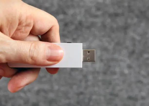 USB Drive in the Hand on the Gray Background