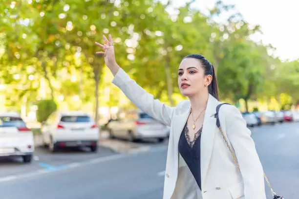 young woman in white jacket demanding a taxicab, blurred background