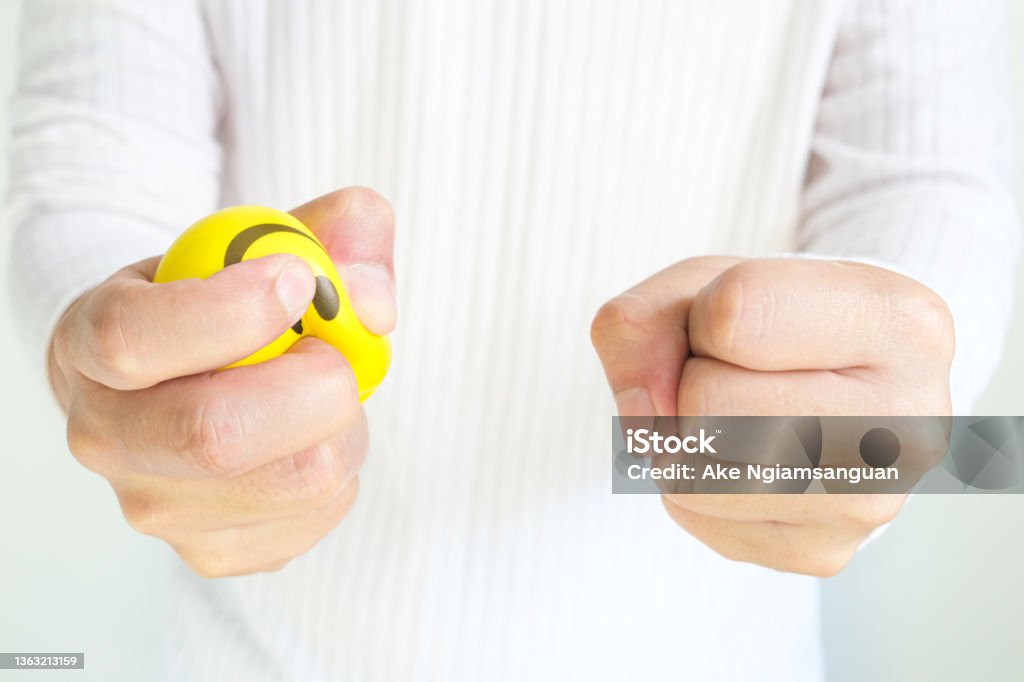 Hands of a young man with a gentle personality He exhibits stressful behavior from work, and he squeezes the yellow ball expressing emotion, anger, displeasure. Medical concepts and emotional regulation Borderline Bar & Grill Stock Photo