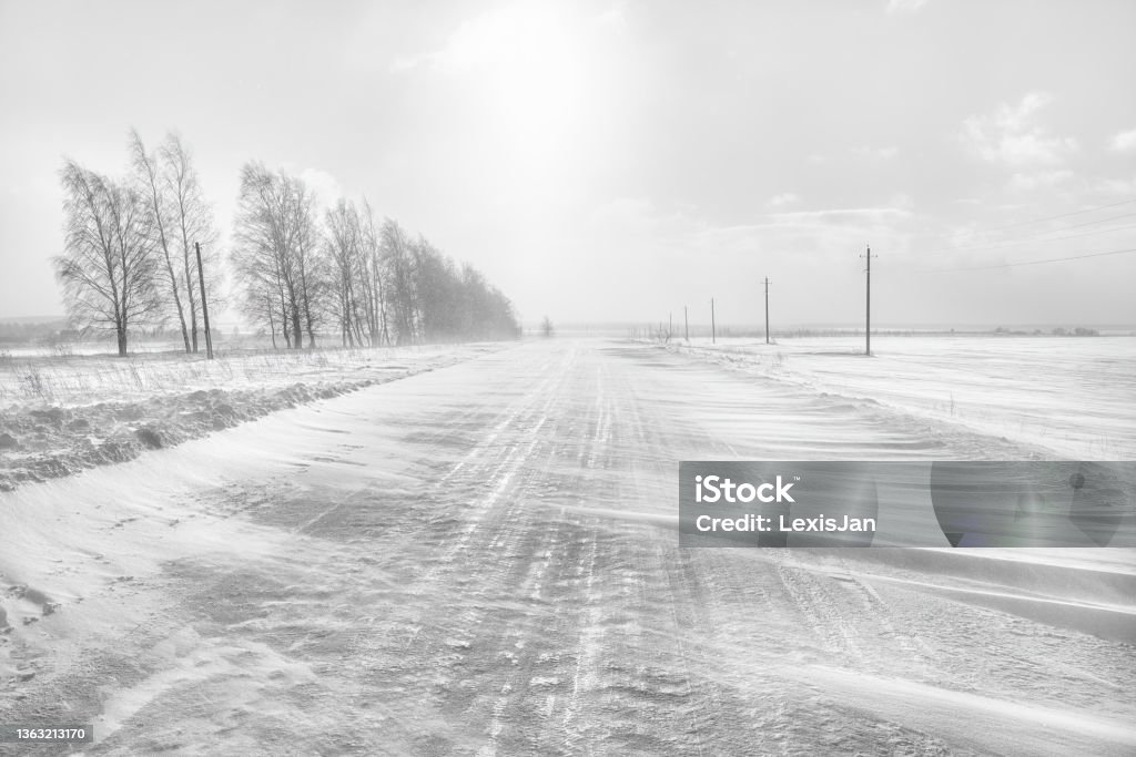 Icy winter road. A blizzard is sweeping the road. Icy winter road. A blizzard is covering the road with snow. Blizzard Stock Photo