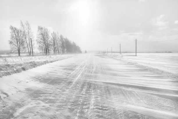 Photo of Icy winter road. A blizzard is sweeping the road.