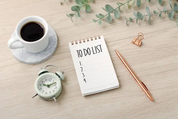 To do list on wooden desk with coffee cup and plant