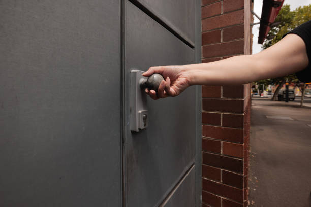 A woman's hand on a gray metal door handle.
