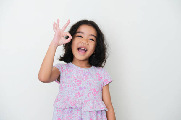 istock Asian kid smiling while giving OK finger sign 1363220359