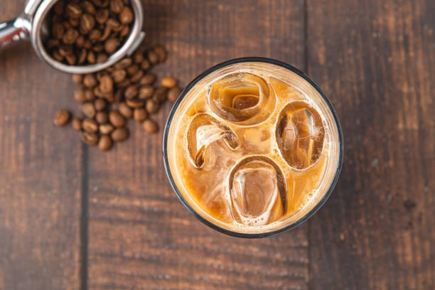 uma xícara de café gelado latte com cubos de gelo colocados em uma mesa de madeira em uma cafeteria - iced coffee - fotografias e filmes do acervo