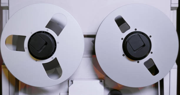 Close-up of recorder with reel-to-reel tape in recording studio.
