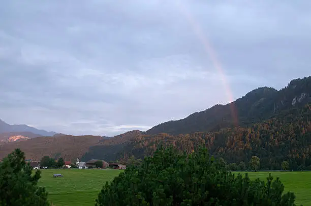 rainbow in the evening in the alps / allgau, mountains and forest in the background