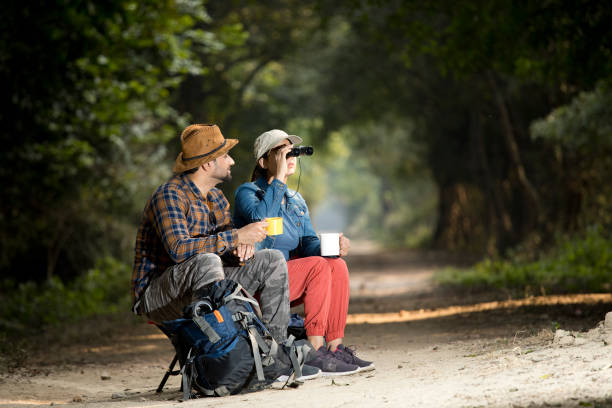 Couple drinking coffee and using binoculars on hiking tour