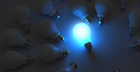 Glowing Light Bulb between the others on blue light background. Leadership, innovation, great idea and individuality concepts. 3d rendering.