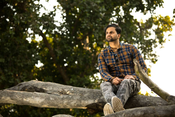 istock Man sitting on tree trunk and admiring nature 1363232700