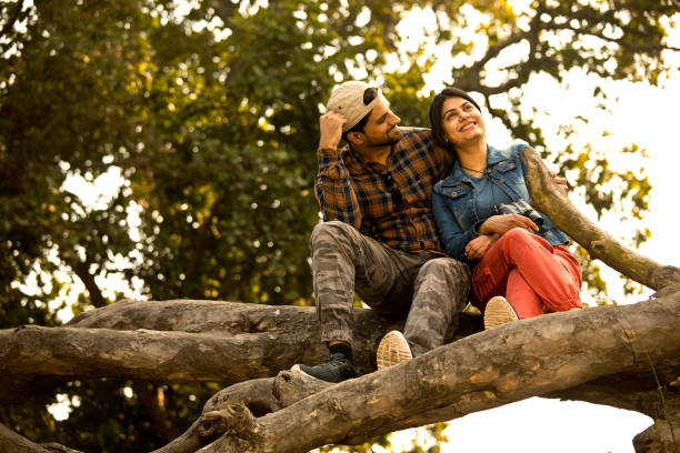 istock Young couple sitting on tree trunk and admiring nature 1363233246