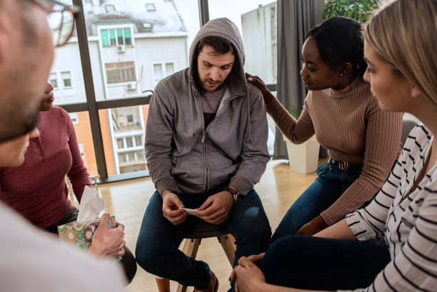 istock Diverse group of people sitting in circle in group therapy session. 1363234587