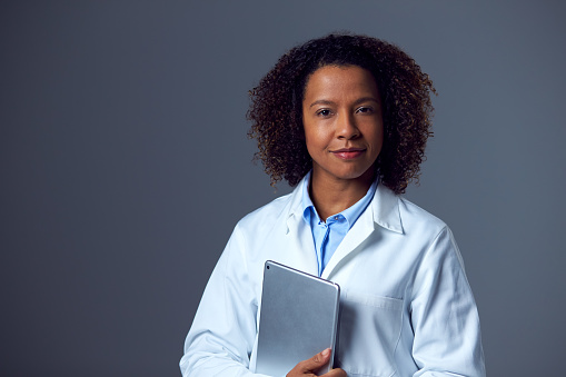 Retrato de estudio de una doctora con bata de laboratorio sosteniendo una tableta digital photo