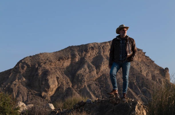 adult man in cowboy hat standing on rock in desert, almeria, spain - western usa mountain peak landscape farm imagens e fotografias de stock