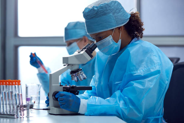 istock Female Lab Workers Wearing PPE Researching In Laboratory With Microscope 1363238241