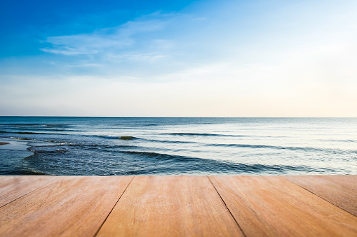 Image of wood table in front of the beach blurred background. Brown wooden desk empty counter in front of the seaside on beautiful ocean and outdoor seashore.