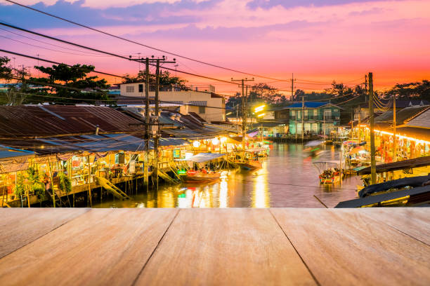 Wooden table in front of the floating market blur background Image of wooden table in front with blurred background of floating market at sunset in Thailand. ratchaburi province stock pictures, royalty-free photos & images