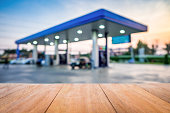 Wooden table in front view of the petrol station at sunset blur background