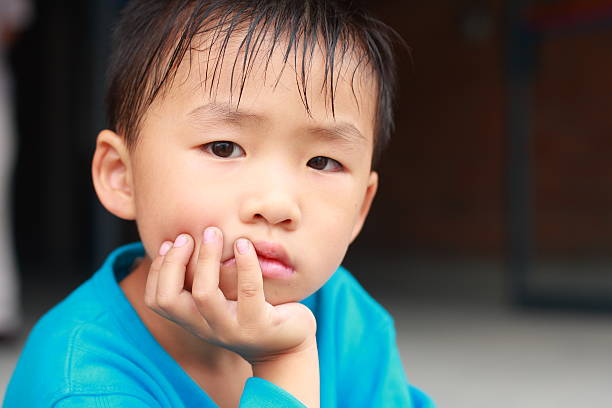 портрет маленького мальчика chinese - child blank expression pensive focus on foreground стоковые фото и изображения