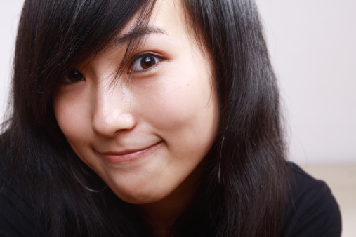 Close-up head shot of model smiling, against white background.