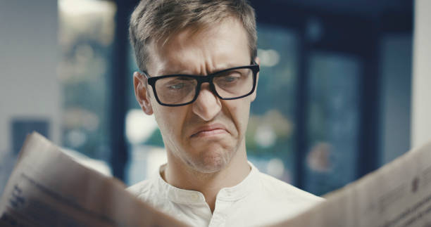 Man reading bad news on the newspaper, he is disgusted and disappointed