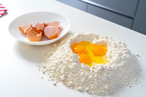 Preparing food: broken eggs in a pile of flour on kitchen counter. High resolution 42Mp indoors digital capture taken with SONY A7rII and Zeiss Batis 40mm F2.0 CF lens