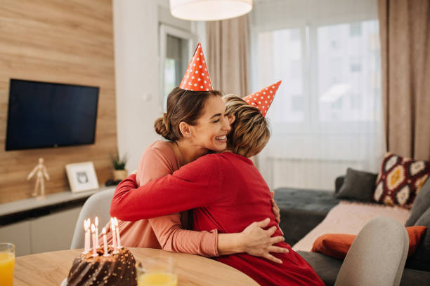 Caucasian mother and daughter celebrating a birthday at home Happy family, Caucasian senior woman celebrating birthday at home with her daughter, having a cake and bonding birthday wishes for daughter stock pictures, royalty-free photos & images