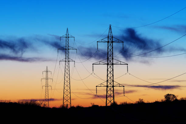 High-voltage electric transmission towers, power lines after sunset stock photo