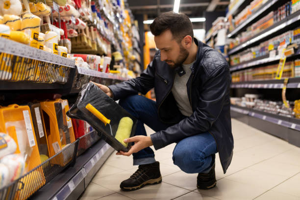 istock a man in a hardware store chooses a roller and a container for paint, construction and repair concept. 1363264703
