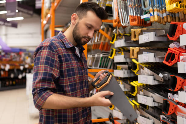istock a man builder at a hardware store chooses a hacksaw for wood next to a rack with a tool for woodworking 1363264814