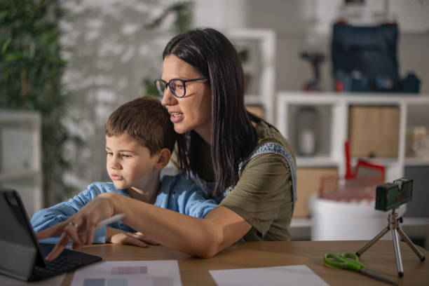 istock Mother sitting at table with her son while they choosing right color for walls on tablet 1363265505