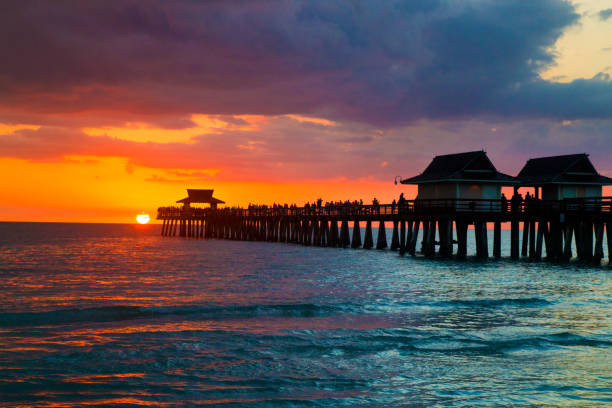 따뜻한 화창한 날 후 아름다운 일몰 동안 나폴리 부두의 플로리다 도시, 멋진 다채로운 설정 일몰 배경으로 바다 위의 부두의 해변 건축 - florida naples florida pier beach 뉴스 사진 이미지