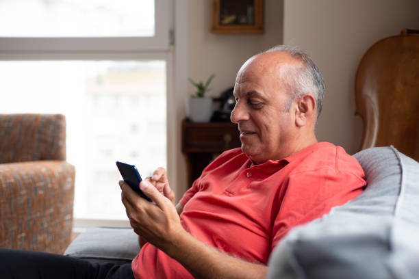istock Smiling senior man using smartphone at home 1363275883
