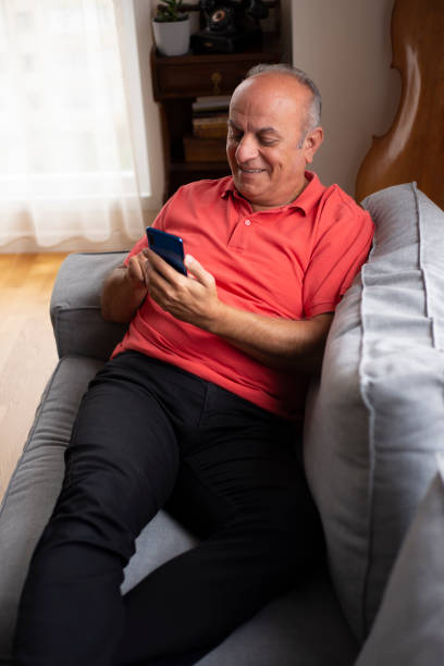 istock Smiling senior man using smartphone at home 1363275978