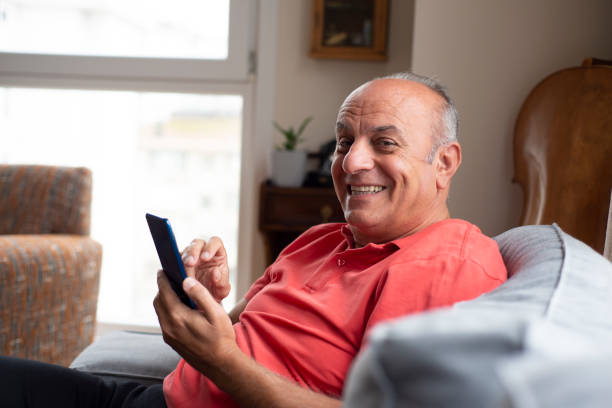 istock Smiling senior man using smartphone at home 1363276098