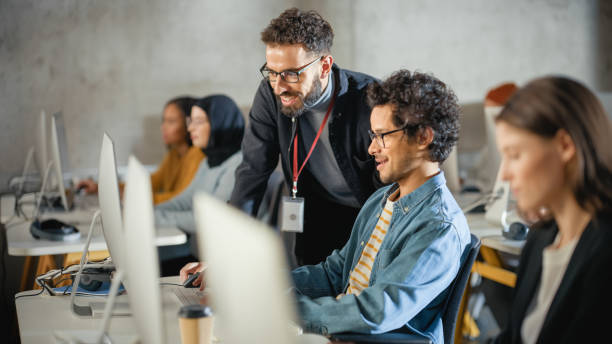 istock Lecturer Helps Scholar with Project, Advising on Their Work. Teacher Giving Lesson to Diverse Multiethnic Group of Female and Male Students in College Room, Teaching New Academic Skills on a Computer. 1363276389