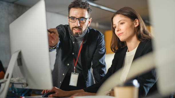 docente aiuta lo studioso con il progetto, consigliando sul loro lavoro. insegnante che tiene lezioni a diversi gruppi multietnici di studenti femminili e maschili nella stanza del college, insegnando nuove abilità accademiche su un computer. - it professional foto e immagini stock